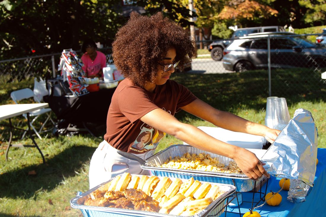 A volunteer serving trays of food at the Harvest Bazaar